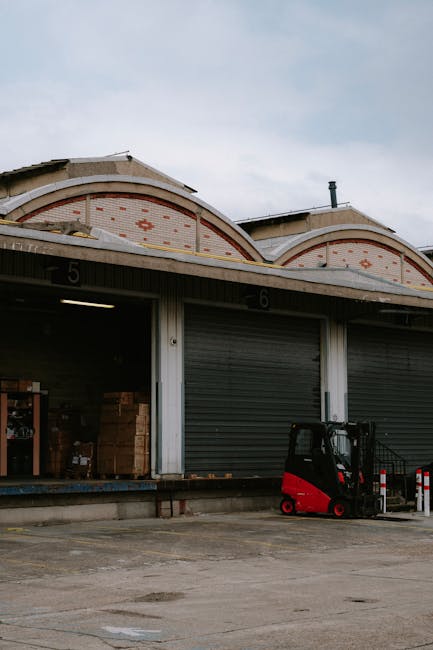 The image shows two adjacent loading bays at a warehouse or industrial building, numbered 5 and 6, with partially open metal shutters revealing interior storage areas containing cardboard boxes and ot